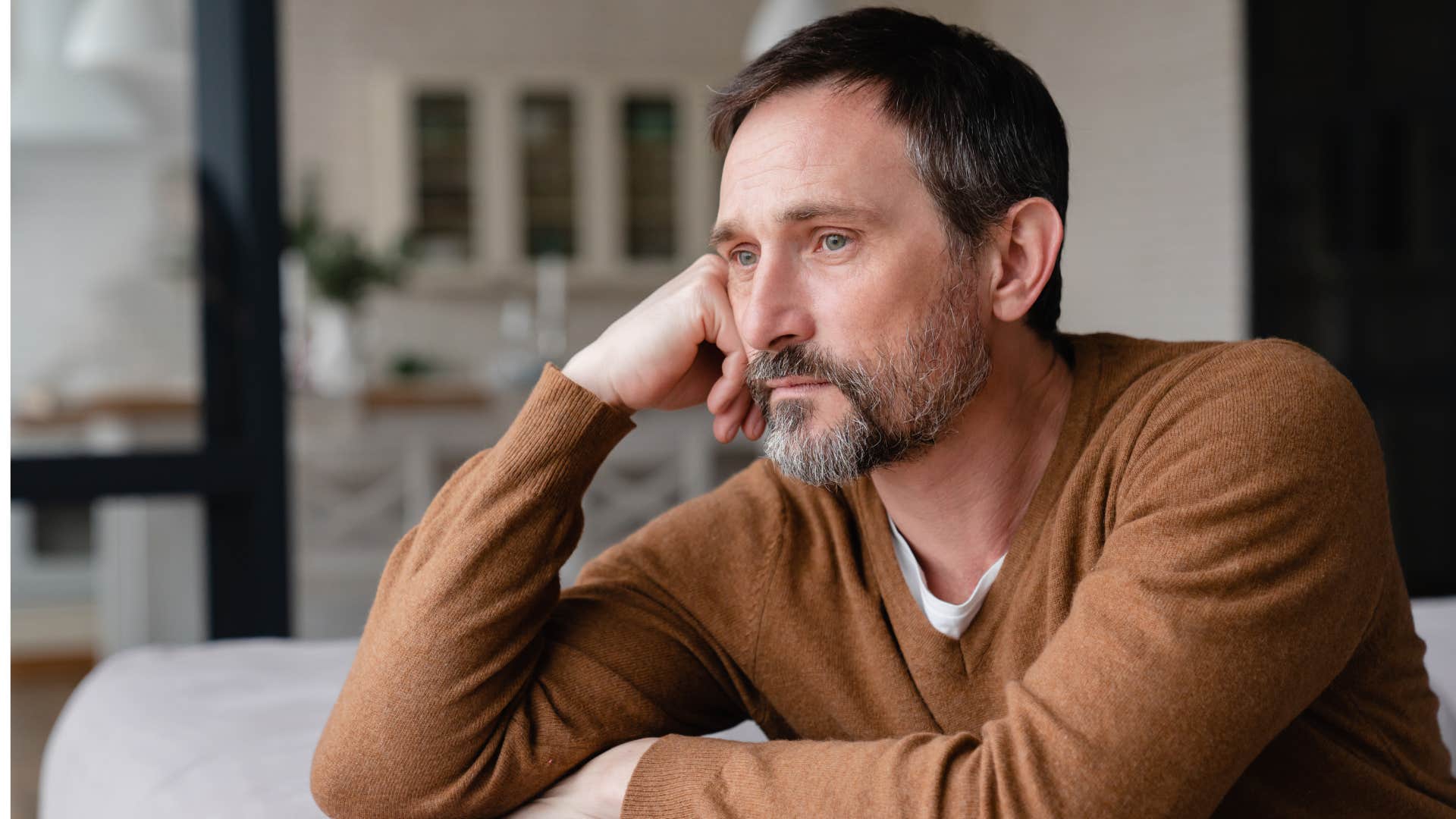 man in brown sweater thinks deeply as a quiet thought keeps coming back that screams i can do more