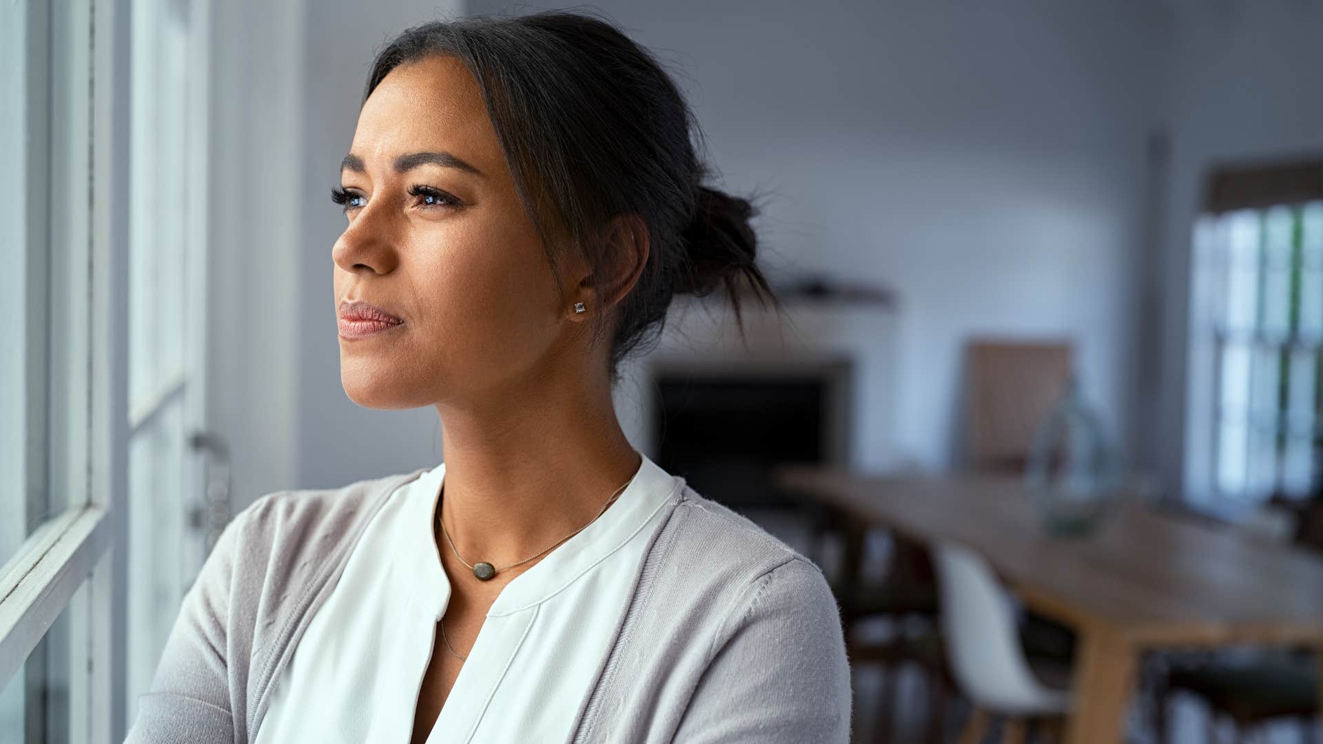 woman in white shirt staring out the window as she becomes brutally honest with herself