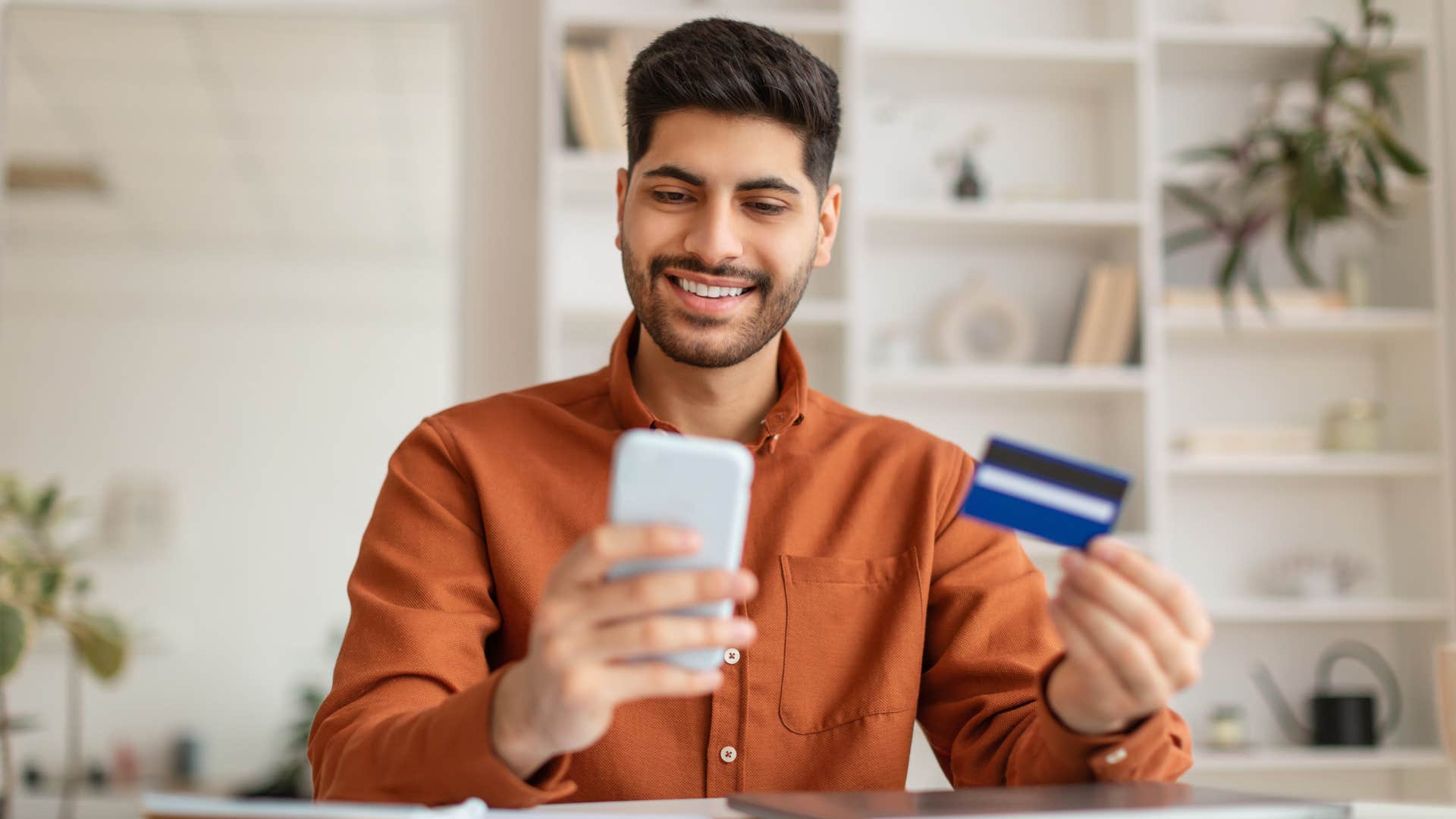 man using credit card to make purchases on phone