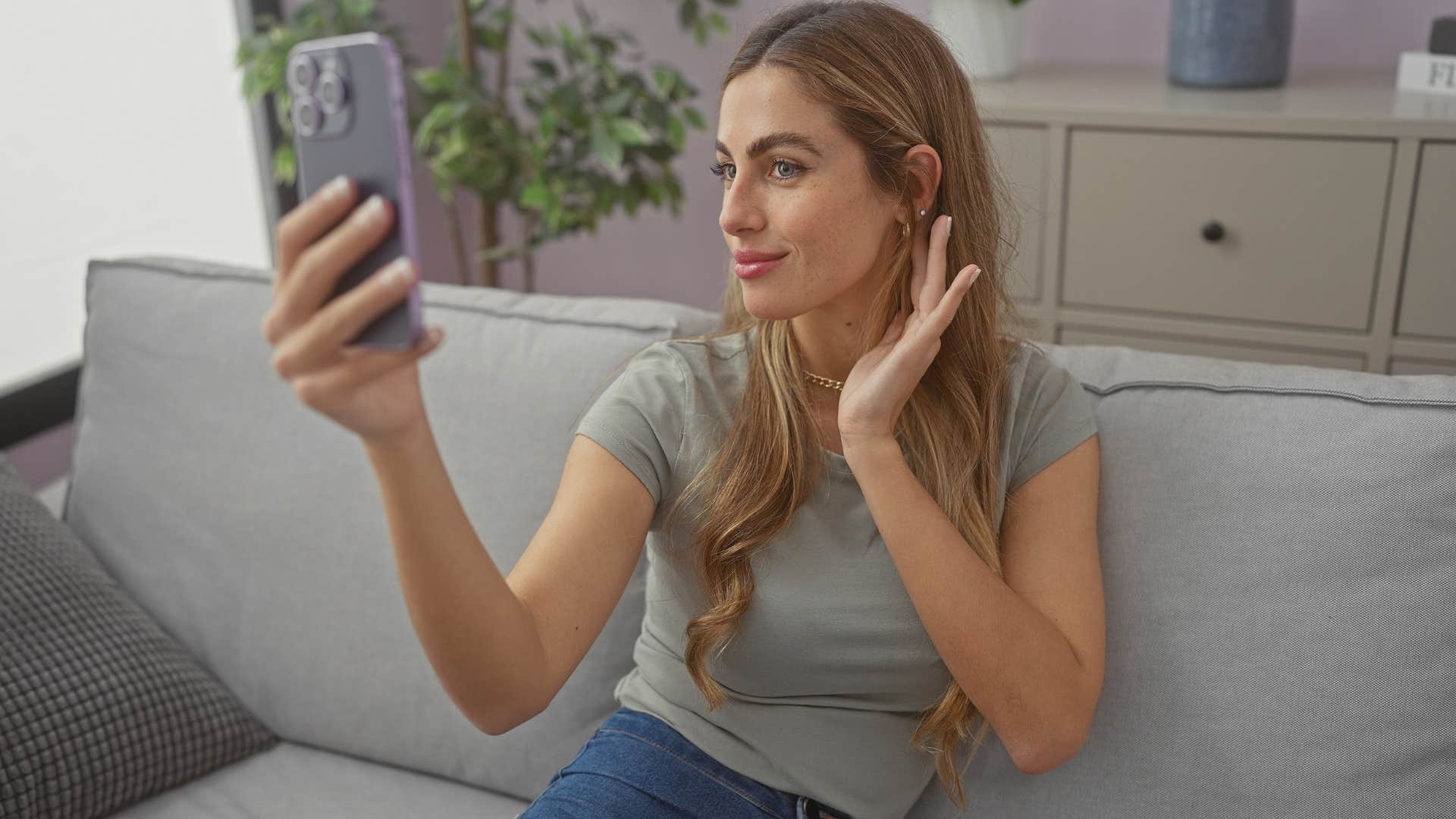 woman faking wealth taking picture with friend's expensive earrings