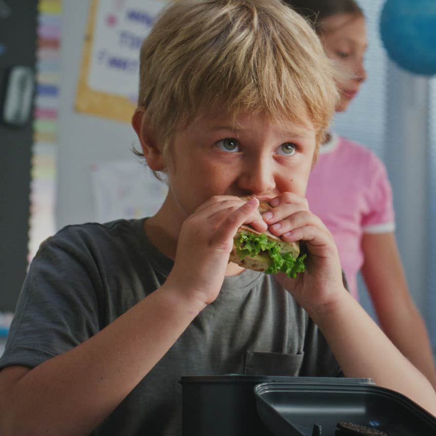 Little boy packing lunches for school and eating.