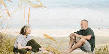 Mature couple, sitting on the beach together.