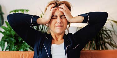 Woman holding her head in pain, illustrating migraine symptoms and warning signs for headaches that feel different or severe