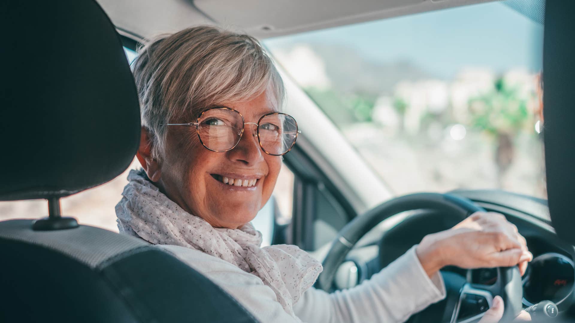 older woman driving a car smiling