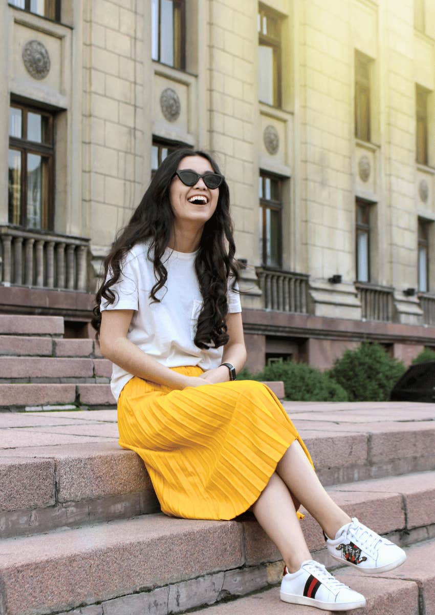 joyful woman sitting on stairs outdoors