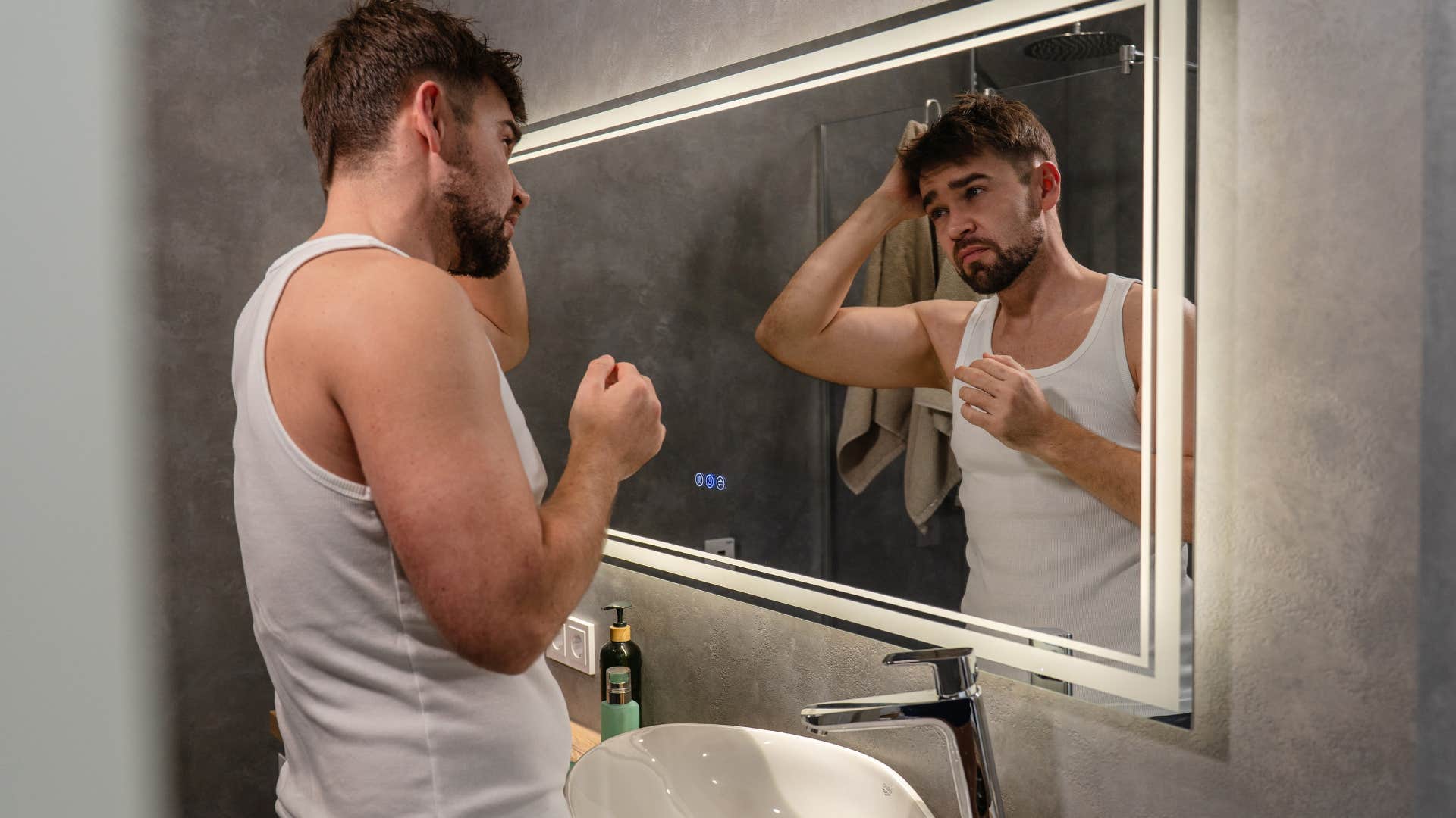 man looking at himself in bathroom mirror