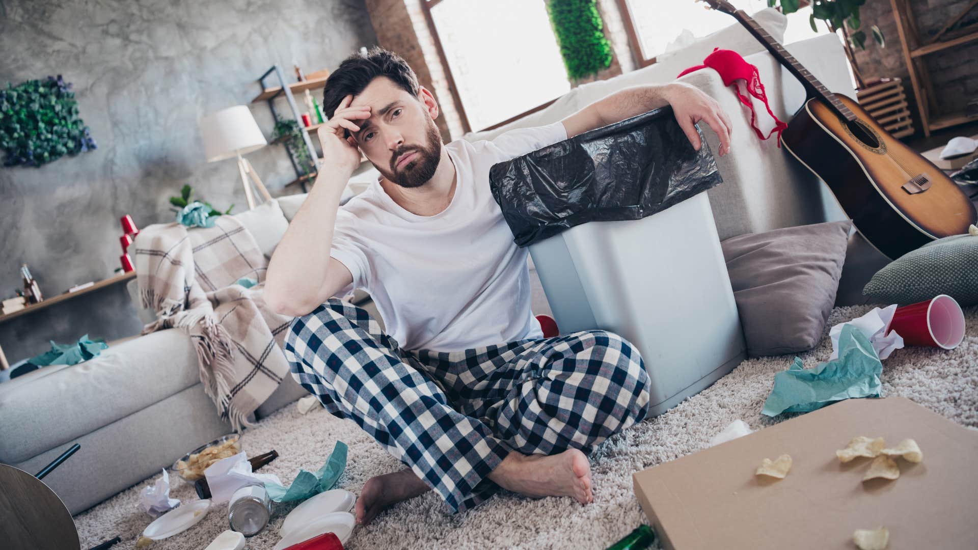 tired messy man sitting around clutter at home