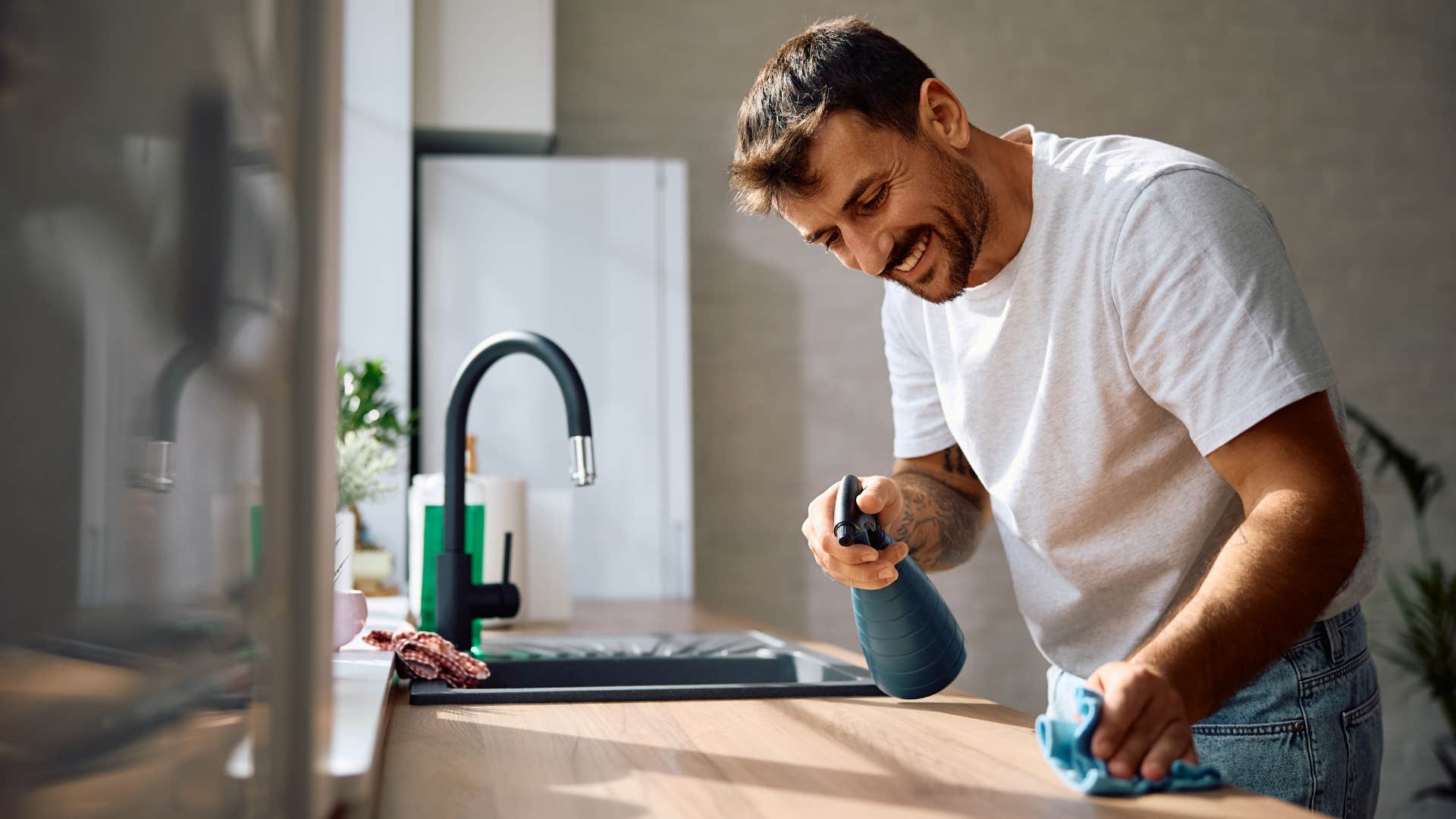 man cleaning counter in kitchen