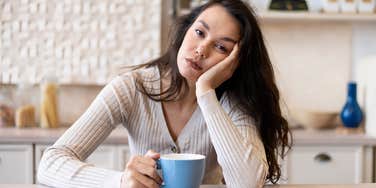 financially afraid woman sitting in her kitchen looking tired