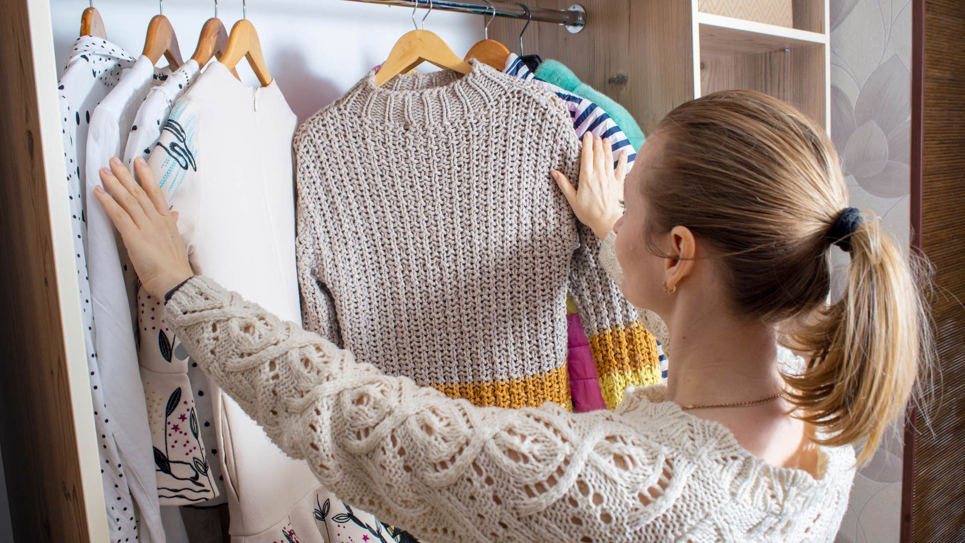 woman looking through clothes in closet
