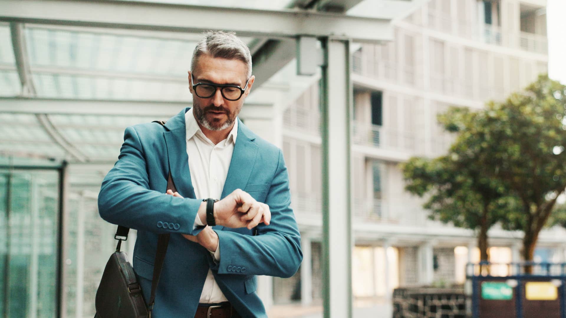 man in blue jacket looks at watch as he thinks about how busy he is