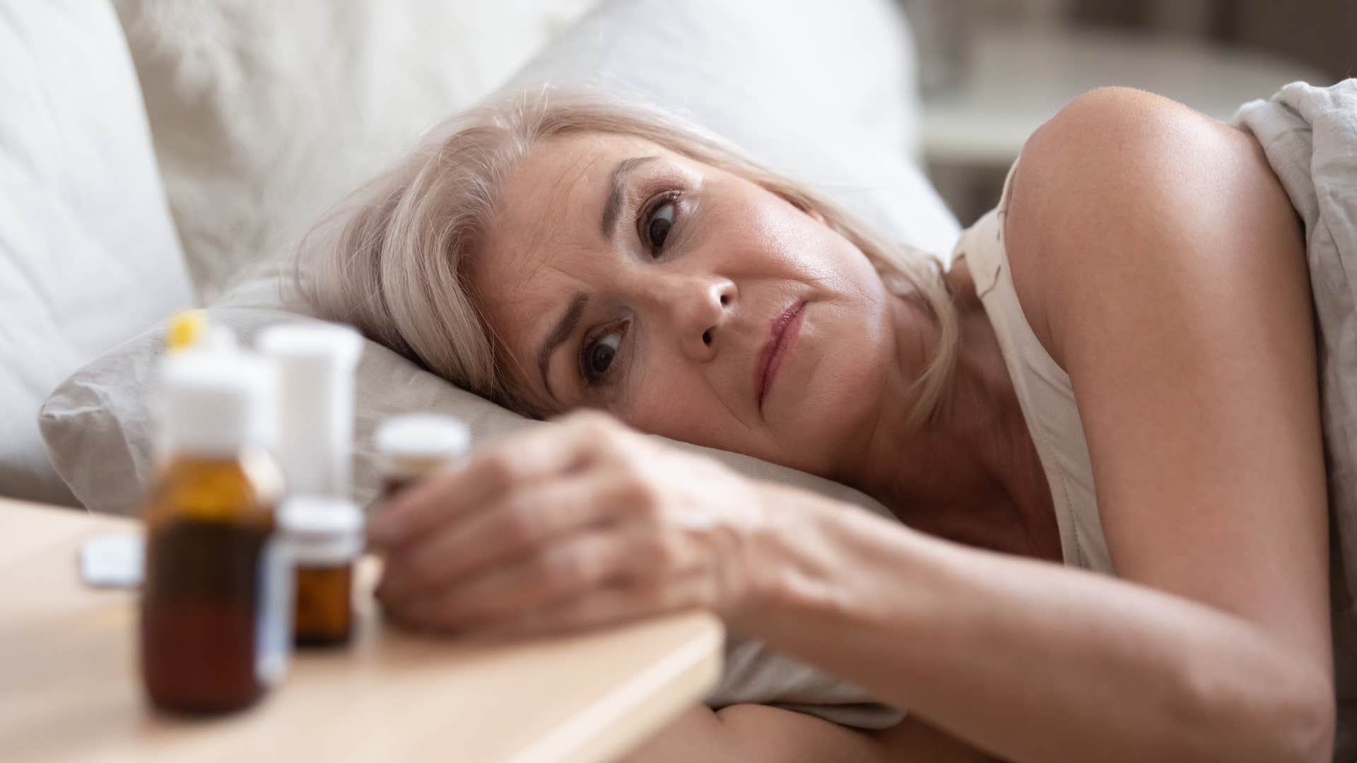 woman reaching for sleep aids to fall asleep