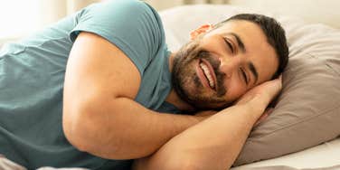 happy man smiling laying in bed about to sleep