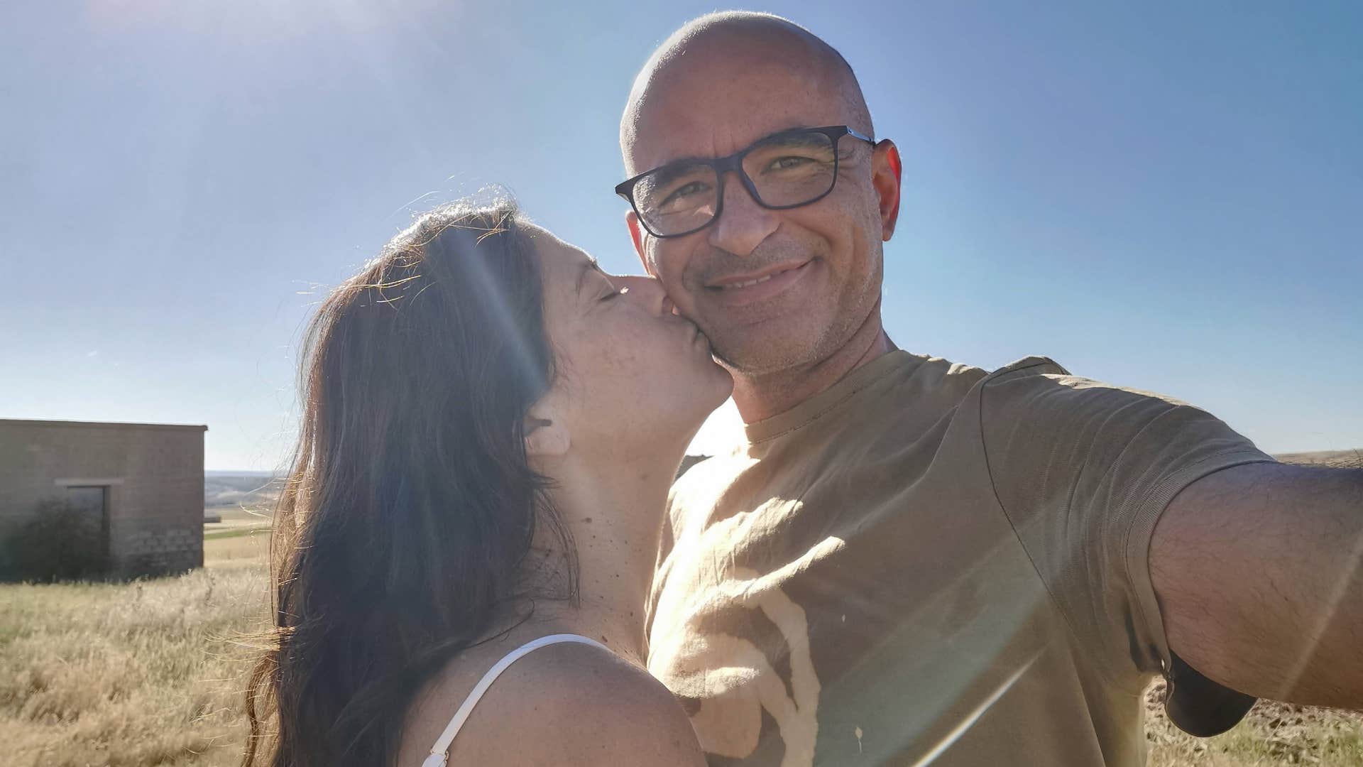 Caring person kisses partner's check showing they grew up loving differently