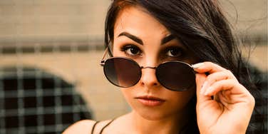 Woman looking over her glasses secretly doesn't like someone 