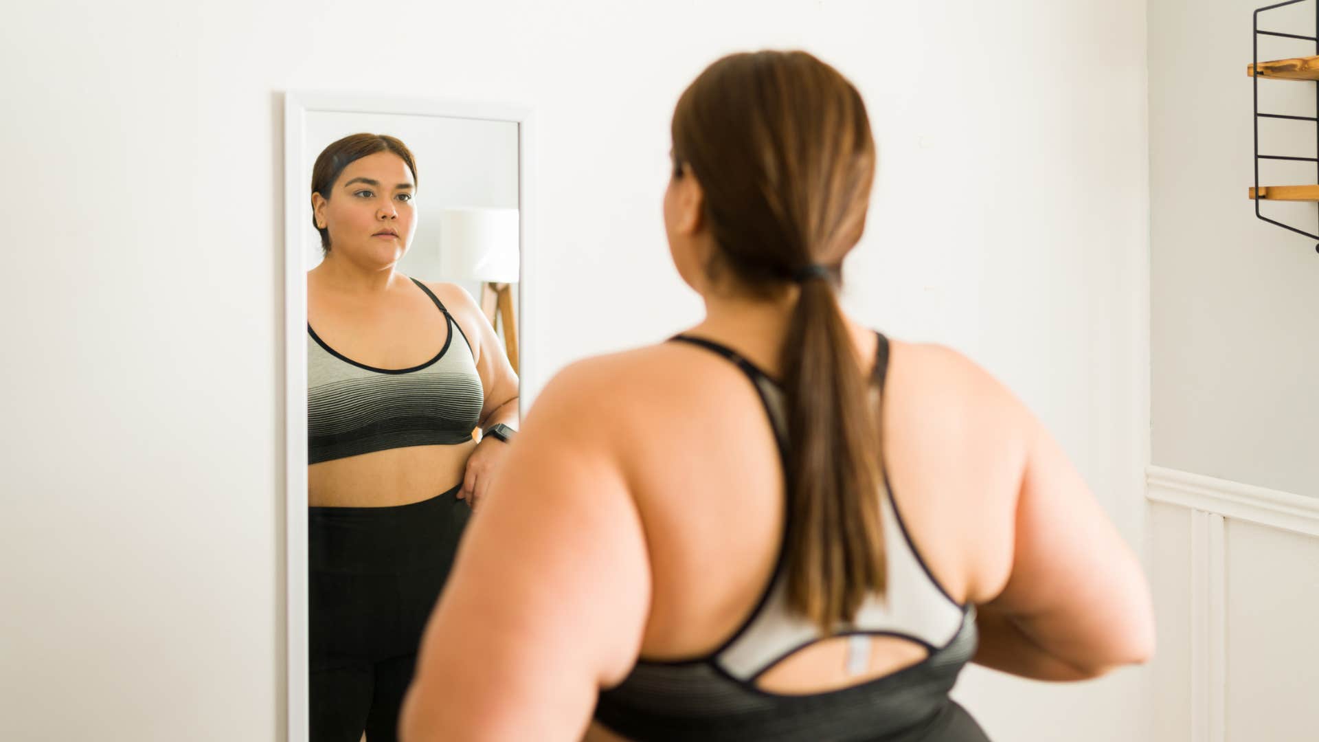 plus-size woman looking at herself in the mirror