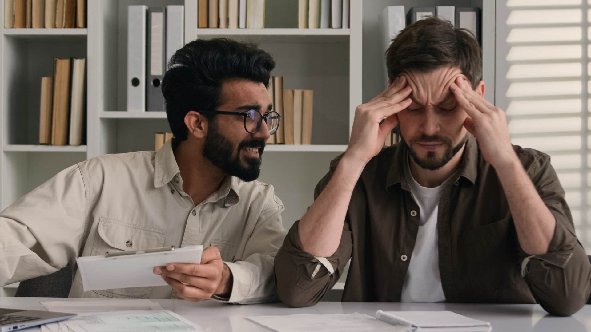 man bragging about money with a stressed co-worker