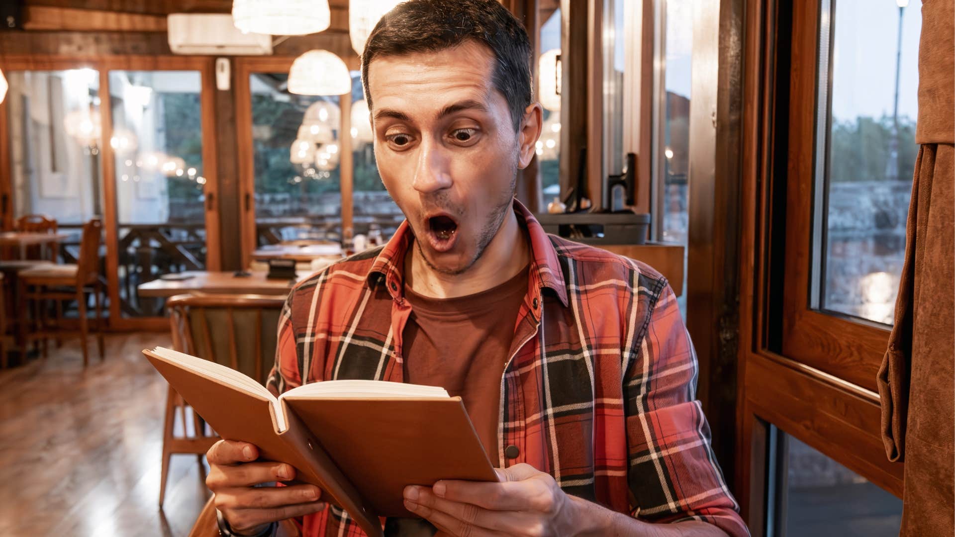surprised man looking at overpriced items on a receipt