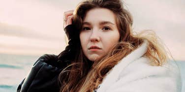 The Art Of Self-Compassion: Simple Habits Of People Who Don't Bully Themselves For Being Human Woman resting her hand on her head in a moment of self-compassion, embodying the simple habits of people who don't bully themselves for being human.