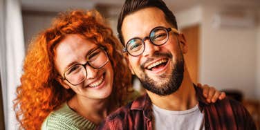 A smiling couple standing close together indoors.