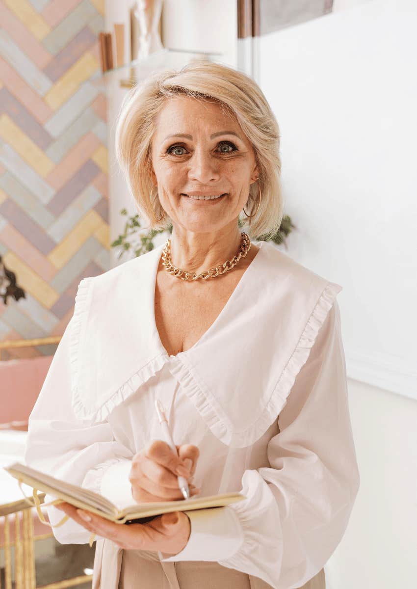 smiling older woman holding a notebook