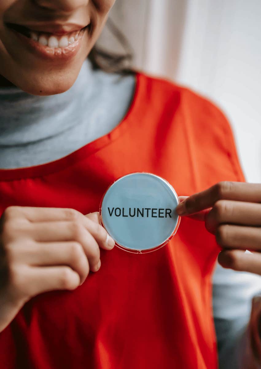 smiling woman holding a volunteer badge
