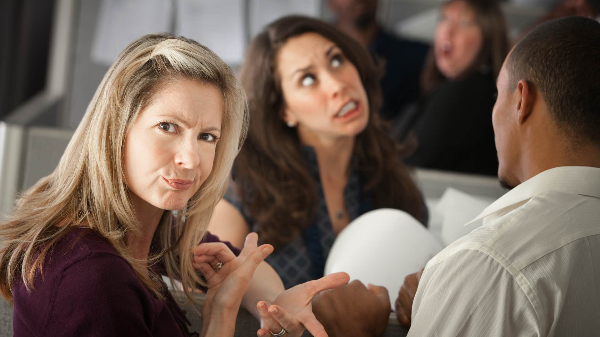 woman annoyed with man interrupting her conversation with friend