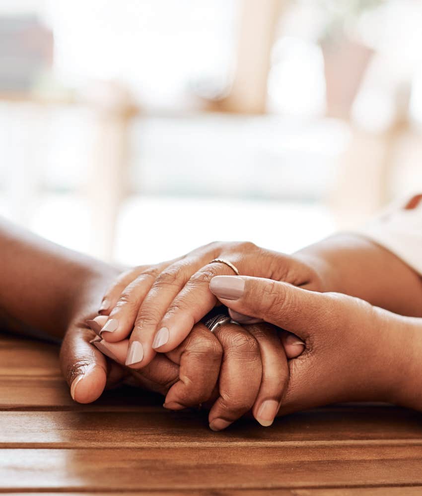 Gentle people hold hands across table showing kindness and gratitude