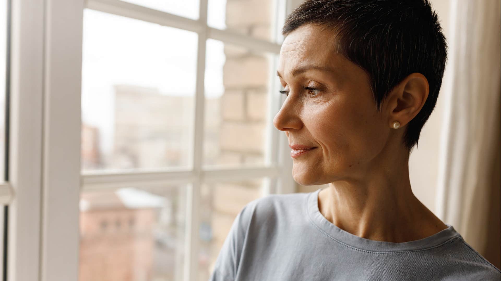 intelligent woman looking out a window and enjoying solitude