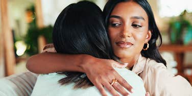 woman hugging friend noticing that she smells bad