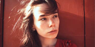 After Years, Happiness Comes Down To These Simple Things Woman with freckles looking off to the side in quiet reflection, appearing thoughtful and emotionally guarded.