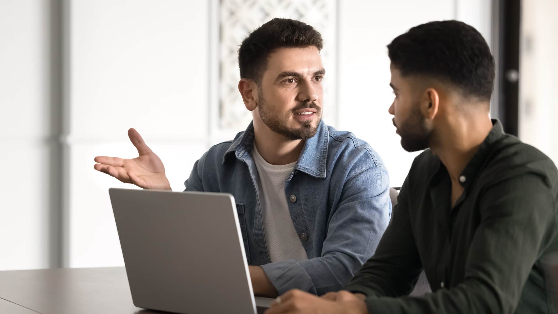 man in gray shirt never over explains himself as he tells coworker something