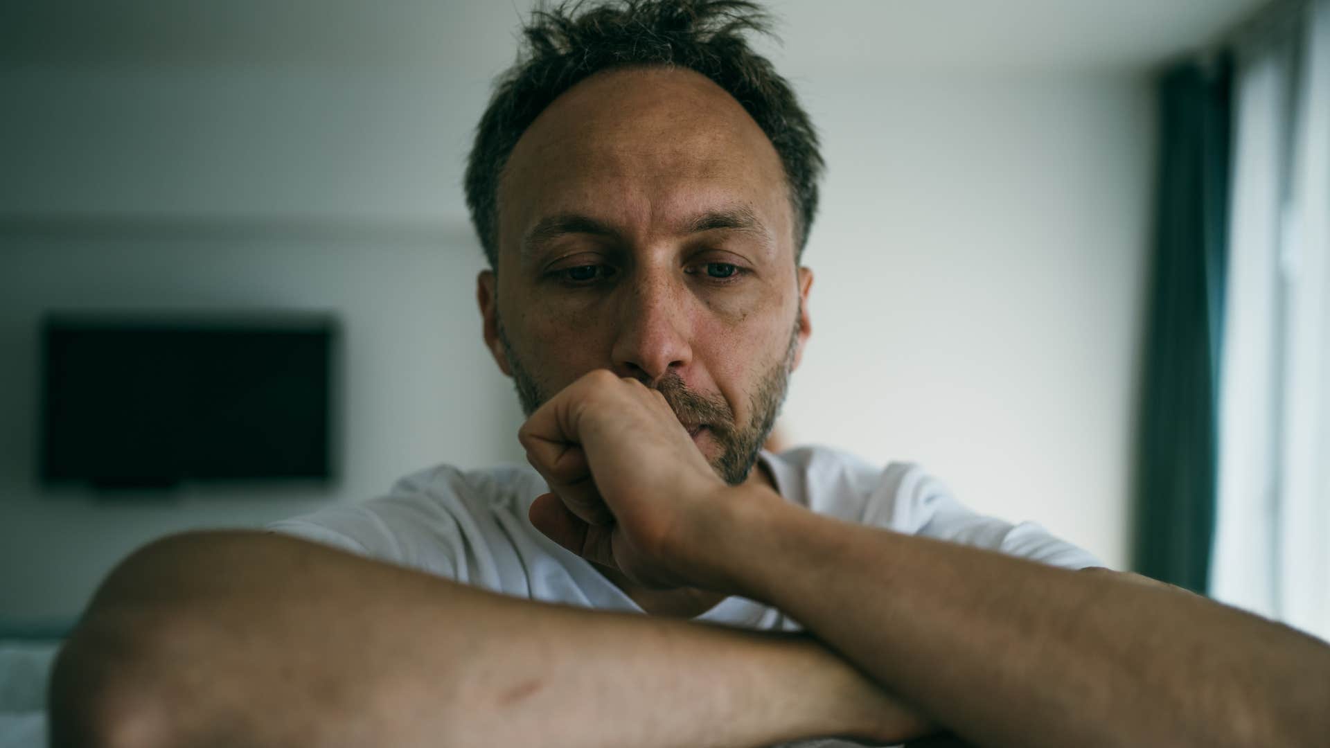 sad man running from discomfort sitting alone at home