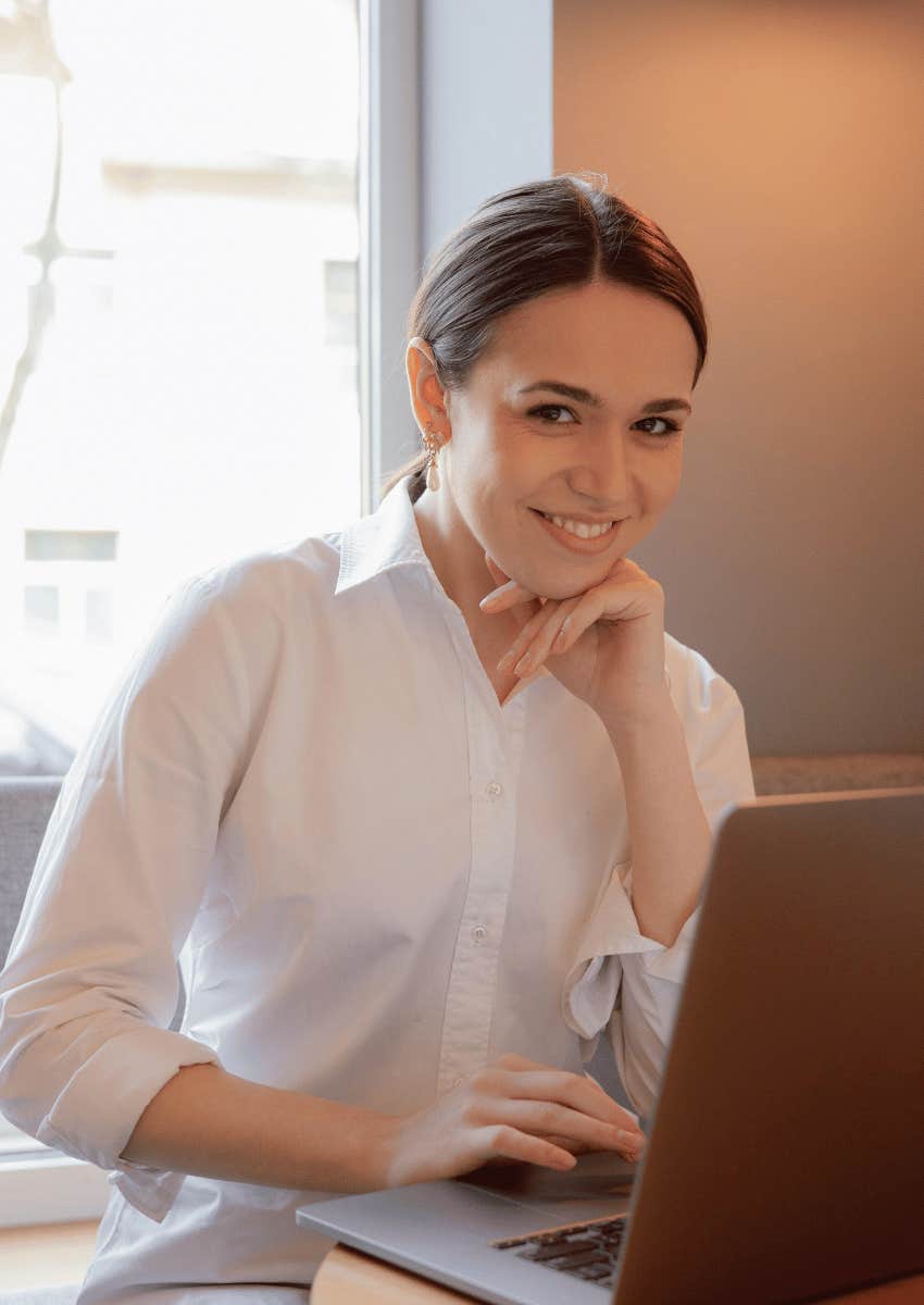 smiling woman sitting with an open laptop