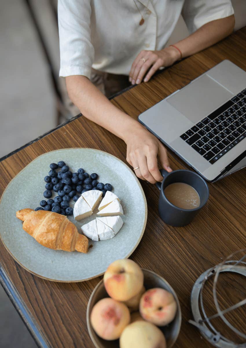 woman with an open laptop snacking