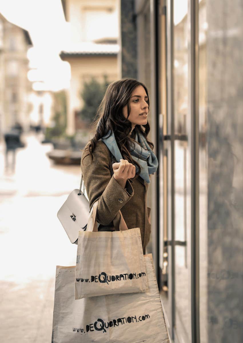 woman window shopping while holding several bags
