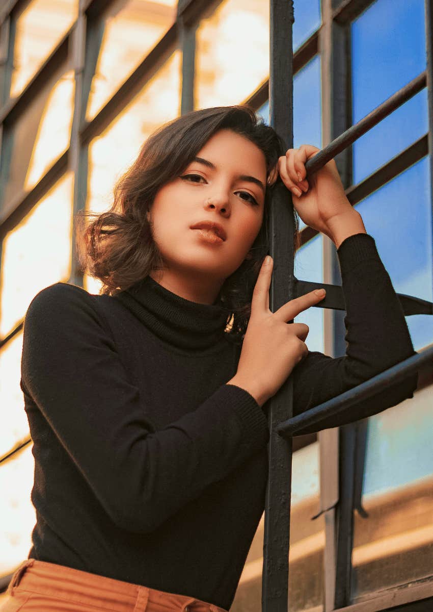 young woman with a serious expression standing outdoors