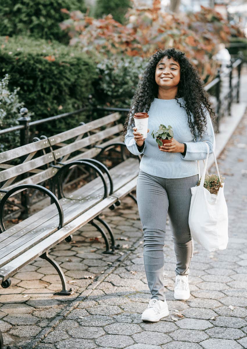 happy young woman walking down sidewalk